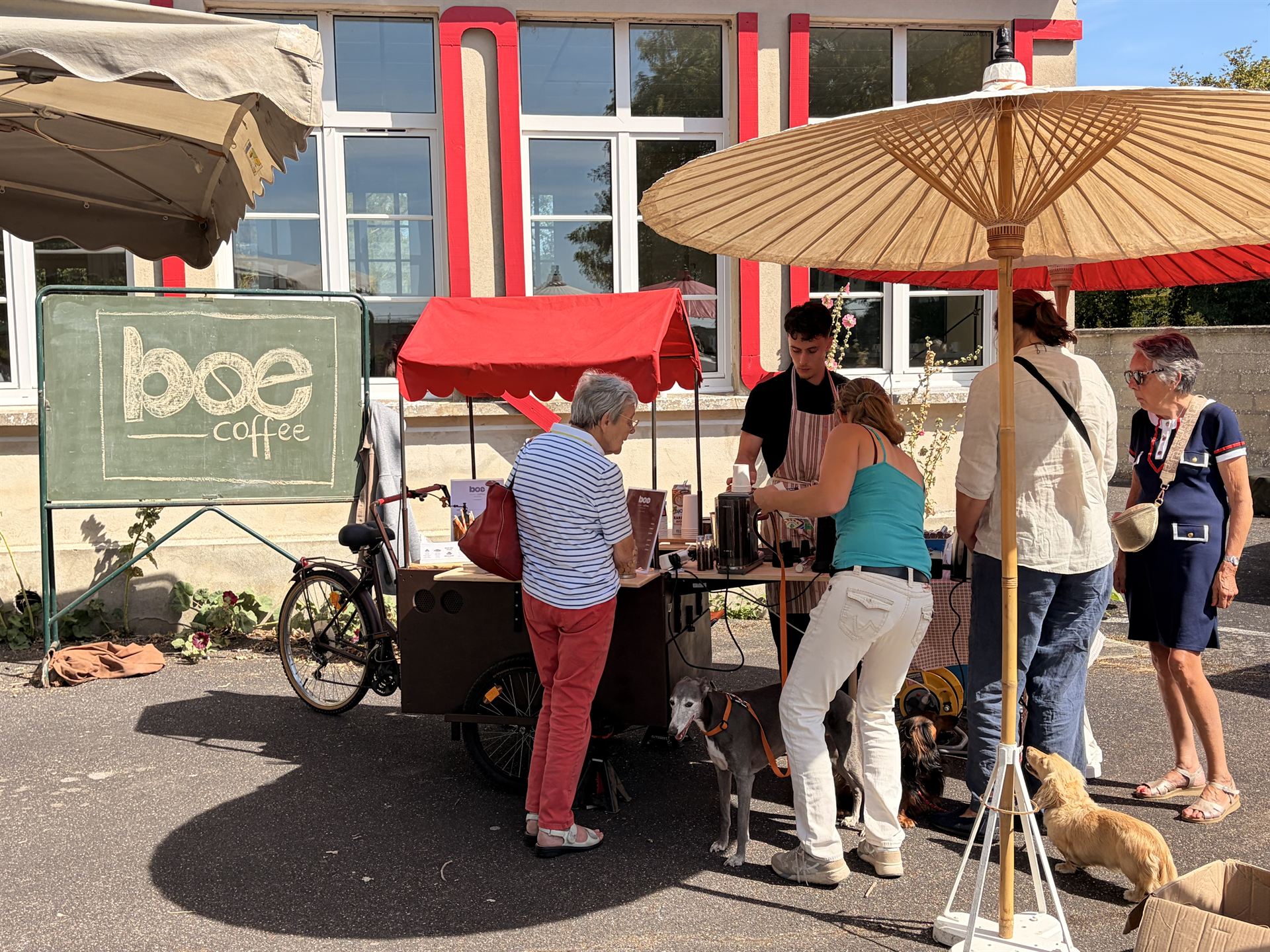 Le triporteur Boé Coffee installé sur un marché en Normandie, clients autour du bar à café mobile